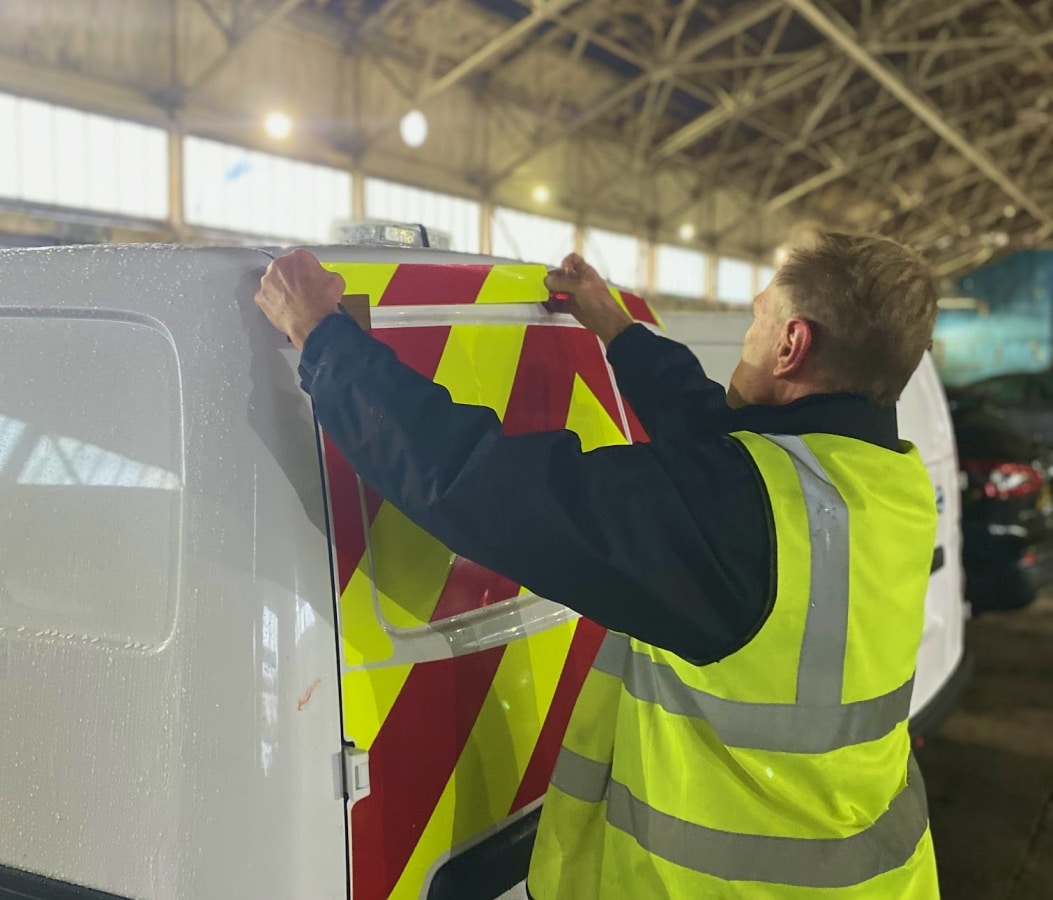 Man applying chapter 8 chevron on a van